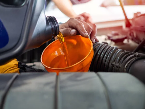 Mano mecánica vertiendo aceite fresco del motor a través del embudo de naranja en — Foto de Stock