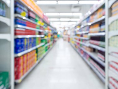 Süpermarketin arka planı bulanık. Alışveriş merkezindeki ürün rafları arasındaki yürüyüş yolu ile bulanık iç görünüm.
