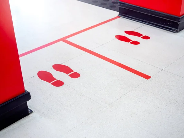 Red footprint and red line on floor in supermarket for warning for keep a safe social distance protect from Coronavirus, social distancing concept.