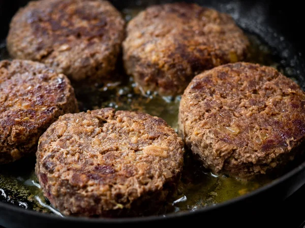 Beef burgers fried in frying pan. Close-up homemade juicy minced meat patties burgers in iron frying pan.