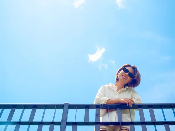 Щаслива Азіатка Білій Сорочці Сонцезахисних Окулярах Стоїть Балконі Синьому Тлі — стокове фото