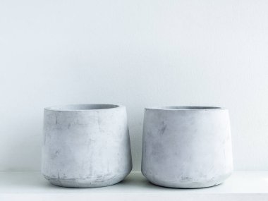 Beton çömlek. Beyaz arka planda beyaz ahşap rafta iki boş modern geometrik çimento ekicisi.