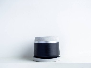 Beyaz raftaki boş modern geometrik beton ekiciler beyaz duvar zemininde kopya alanı ile izole edilmiş. Güzel siyah ve gümüş renkli çimento tenceresi.