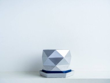 Beyaz raftaki boş modern geometrik beton ekiciler beyaz duvar zemininde kopya alanı ile izole edilmiş. Güzel mavi ve gümüş renkli çimento tenceresi.