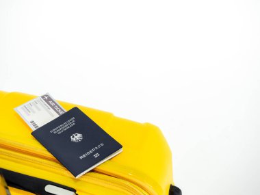 Sarı bavuldaki pasaport ve uçak bileti beyaz arka planda izole edilmiş ve fotokopi alanı var. Sarı bavulla Almanya 'nın mavi pasaportu, seyahat konsepti.