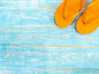 Plaj aksesuarları, portakal rengi terlikler, kopyalanmış mavi ahşap döşeme. Seyahat ve tatil yaz tatili geçmişi, üst manzara.
