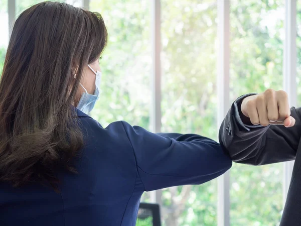 Elbow bump. Business woman wearing medical face mask and use elbow to bump into greeting with copy space. Safe greetings. New way to greet, instead of shaking hands to avoid the spread of coronavirus.