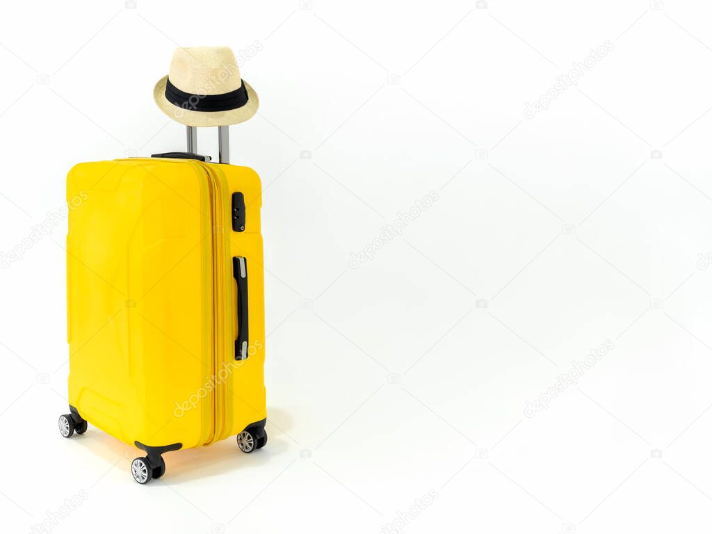 Yellow suitcase with straw hat on isolated on white background with copy space. Large yellow luggage or travel bag on wheels with straw hat on metal long handle, summer holiday traveling concept.