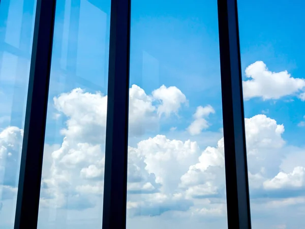 Beautiful clouds and blue sky through silhouette large window frames, view from inside the building.
