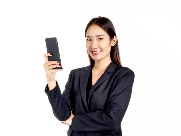 一位年轻迷人的亚洲女商人穿着西服 她用智能手机和照相机 脸上带着淡淡的微笑 背景是白色的 — 图库照片