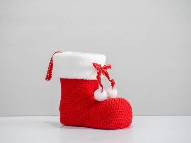 Beyaz arkaplanda beyaz kürklü ve kurdeleli kırmızı Noel çizmesi. Noel Baba hediyesini, Noel kutlamasını ve kış mevsimi dekorasyonunu sembolize eden bayram süsü..