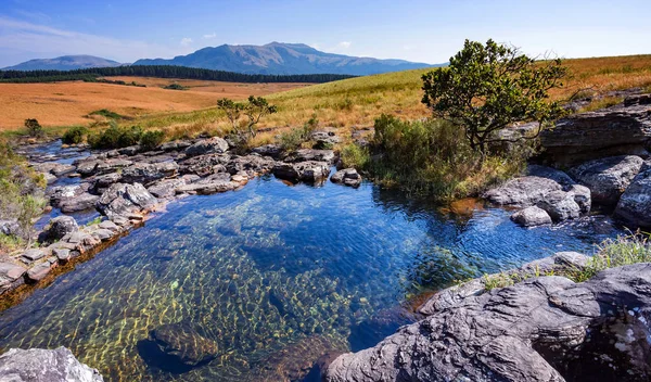 View of rock pools in South Africa with mountains in the background.