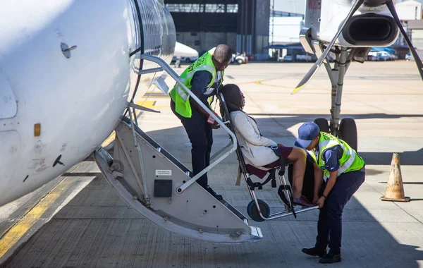 Behinderten Passagieren beim Einsteigen in Flugzeug geholfen — Stockfoto