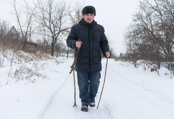 Зрелый Человек Идущий Снежной Дороге Помощью Деревянных Палок — стоковое фото