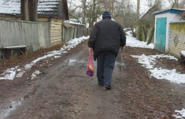 Baston ile yaşlı köylü kırsal köy Pidstavky, Sumskaya oblast, Ukraine boş bir caddede gidiyor