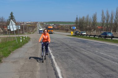 Dnepropetrovsk, Ukrayna - 07 Nisan 2016: Olgun kadın Dnepropetrovsk şehir dışına bir karayolu üzerinde Bisiklete binme