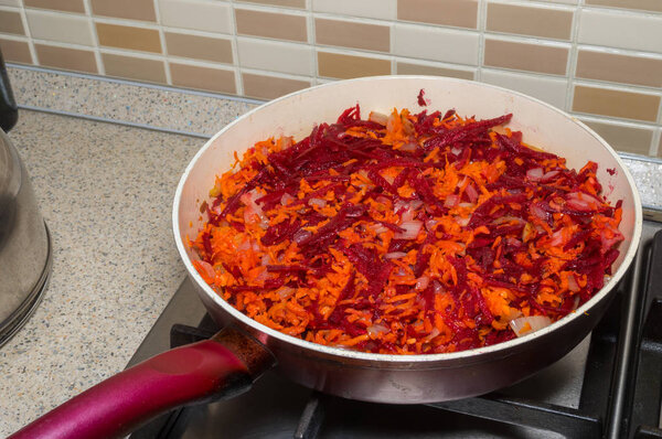 Fried onion, beetroot and carrot on frying pan closeup. It ingredients for Ukrainian red-beet soup called borscht