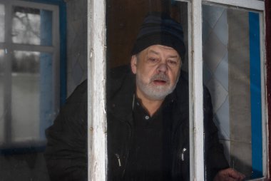 Komuta sizde yalnız yaşayan kırsal Ukraynalı köy gözetleme out onun eski evi kirli pencereden