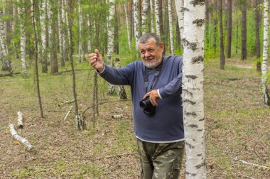 Kamera ayakta yakınındaki birch bahar ormandaki yaşlı adam
