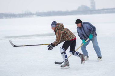 Dnipro, Ukrayna - 28 Ocak 2018: Genç kavga Pak için yaşlı adamın donmuş nehir Dnipro Ukrayna'daki Tarih hokey oynarken adam