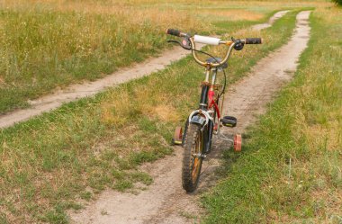 Ana sayfa üzerinde yol kenarında bekleyen paslı çocuklar 3 tekerlekli bisiklet