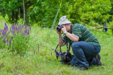 Enthusiastic mature photographer taking a photo of wild butterfly