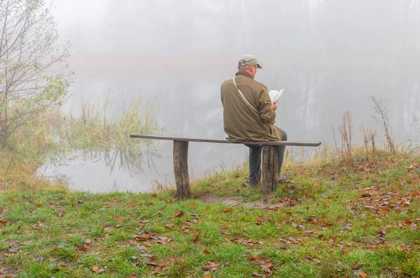 Ώριμος Άνδρας Ανάγνωση Στην Όχθη Του Ποταμού — Φωτογραφία Αρχείου