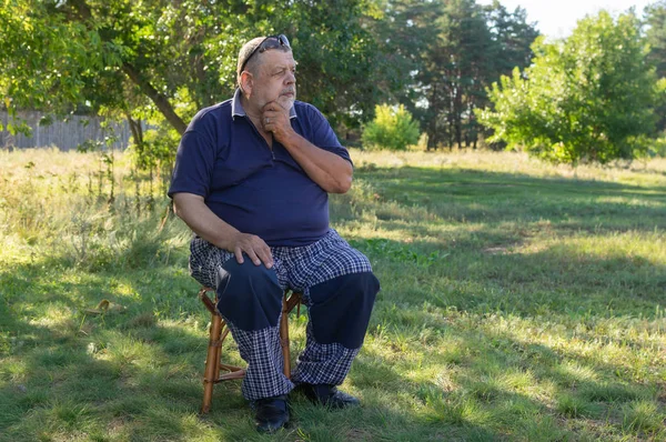 Nice Outdoor Porträtt Ukrainska Omtänksamma Senior Man Sitter Pall Sommarträdgård — Stockfoto