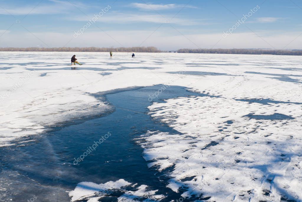 Winter landscape - lonely fishermans on a frozen river.