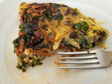 Çatal ve manaltın omlet ile yağlı bir plaka üzerinde yakın görünüm