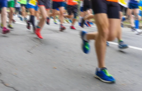 Blurry sport background - people feet  running on an asphalt road during Marathon race