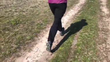 Bahar mevsiminde toprak yolda tek başına koşan siyah pantolonlu bir insan.