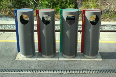 Voss, Norway - June 25, 2018: Four garbage bins for different sorts of waste on the platform of Voss railway station. clipart