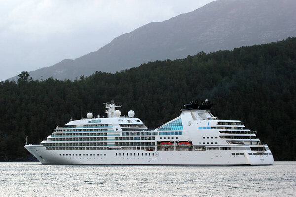 Aenes, Norway - June 19, 2018: MV Seabourn Quest, a luxury cruise ship of Seabourn Cruise Line, in Maurangsfjorden near Furebergsfossen waterfall in Kvinnherad, Hordaland county, Norway.