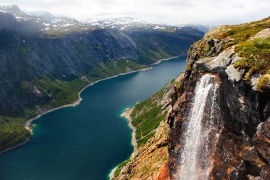 Lake Ringedalsvatnet, karla kaplı dağlar ve Trolltunga, Norveç'e yolda bir şelale. Güzel İskandinav manzara.