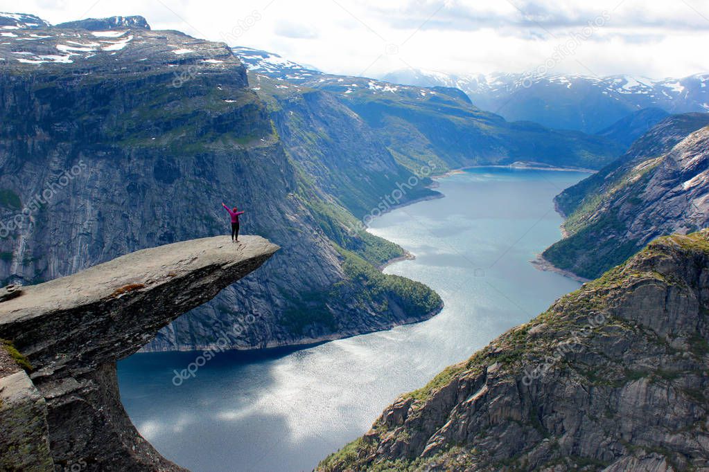A woman stands on Trolltunga (Troll's Tongue), the cliff above the lake Ringedalsvatnet, a popular tourist destination in Hordaland county, Norway.