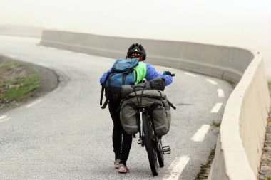 Bir kadın bir bisiklet gezisi touring bisikleti dağ yolun Sisli havalarda iter.