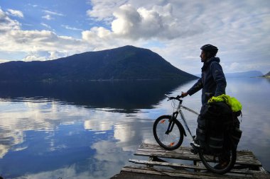 Dimmelsvik, Norveç - 17 Haziran 2018: bir bisikletçi Bisiklet standları Hardangerfjord, arıyorum bir iskelede turne ile ikinci en uzun fiyort Norveç'te.