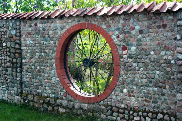 Stone garden fence with round window shaped like a wheel