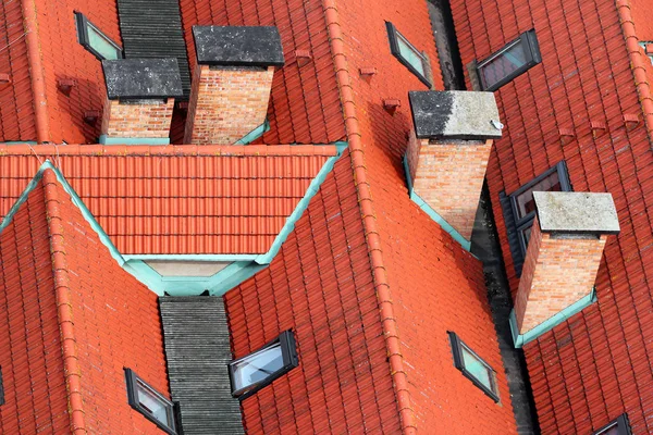 Vista aerea di tetti piastrellati rossi con ciminiere e finestra sottotetto — Foto Stock