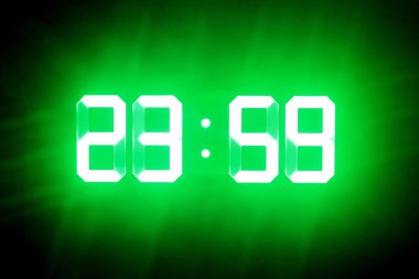 Karanlıkta yeşil parlayan rakamlar 23:59'da. Zaman gece yarısına bir dakika dır..