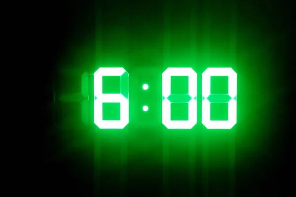 Relojes digitales brillantes verdes en el espectáculo oscuro 6: 00 hora —  Fotos de Stock