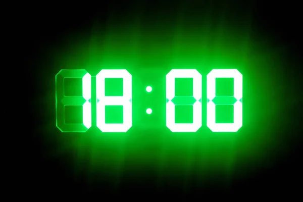 Green glowing digital clocks in the dark show 18:00 time — Stock Photo, Image