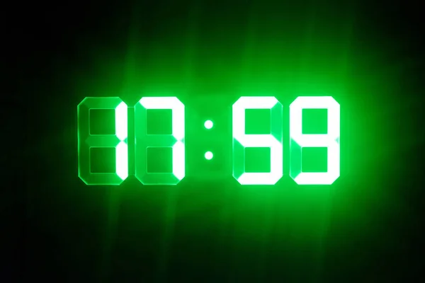 Green glowing digital clocks in the dark show 17:59 time — Stock Photo, Image