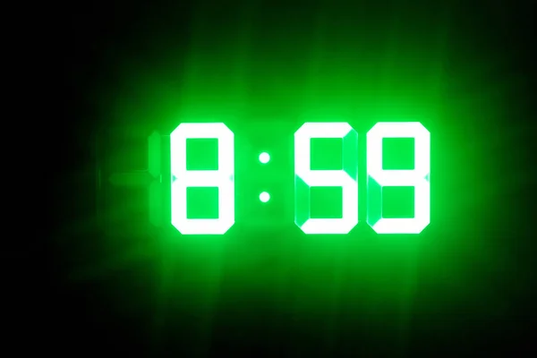 Relojes digitales brillantes verdes en el espectáculo oscuro 8: 59 tiempo —  Fotos de Stock