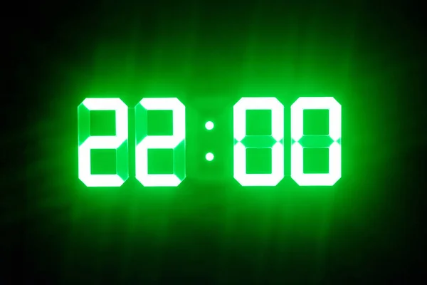 Green glowing digital clocks in the dark show 22:00 time — Stock Photo, Image