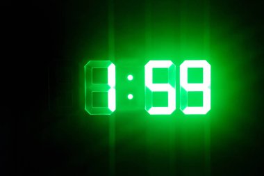 Karanlıkta yeşil parlayan dijital saatler 01:59 zaman göstermek