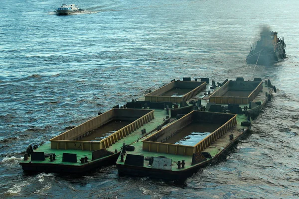 Tug boat tows empty barges, filled with water to pass under low bridges — Stock Photo, Image