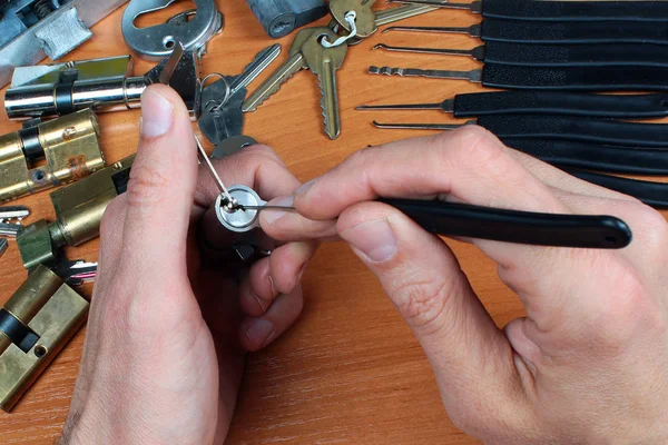 Locksmith picks a cylinder lock with lockpick and tension wrench
