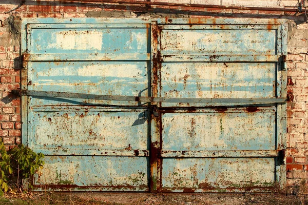 Stare metalowe drzwi garażowe. Płukanie farby i rdzy na bramach opuszczonego budynku. — Zdjęcie stockowe